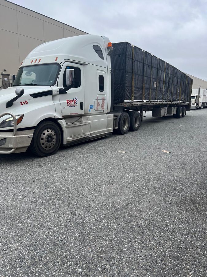 Right Path Trucking Freightliner Cascadia with a covered flatbed load at a loading dock