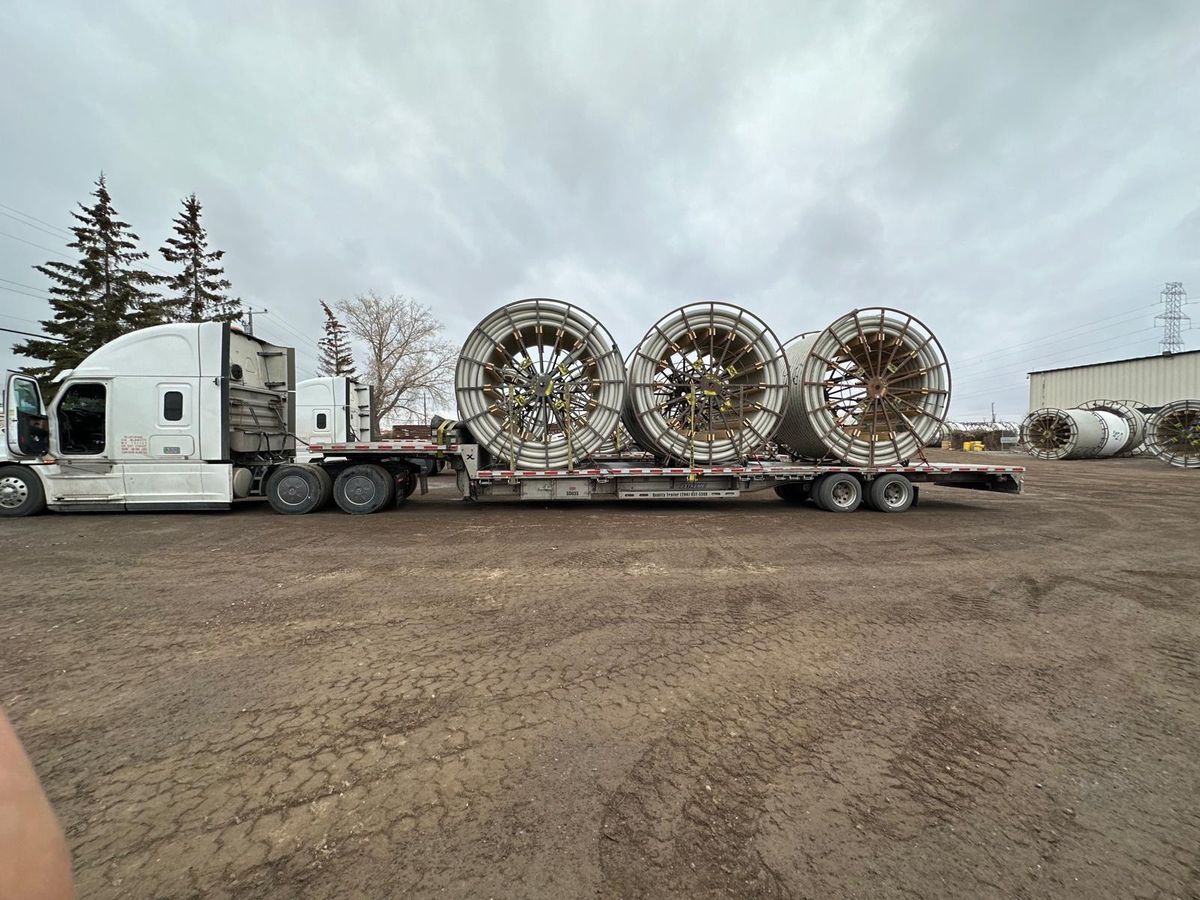 Oversized industrial cable reels chained down on a Right Path Trucking step deck trailer