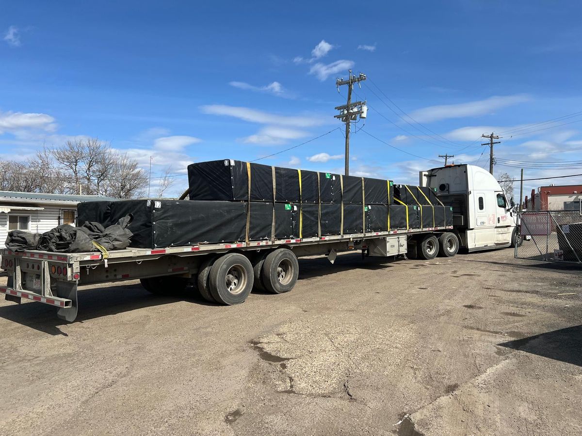 Tarped and strapped flatbed load secured for transport on a Right Path Trucking trailer